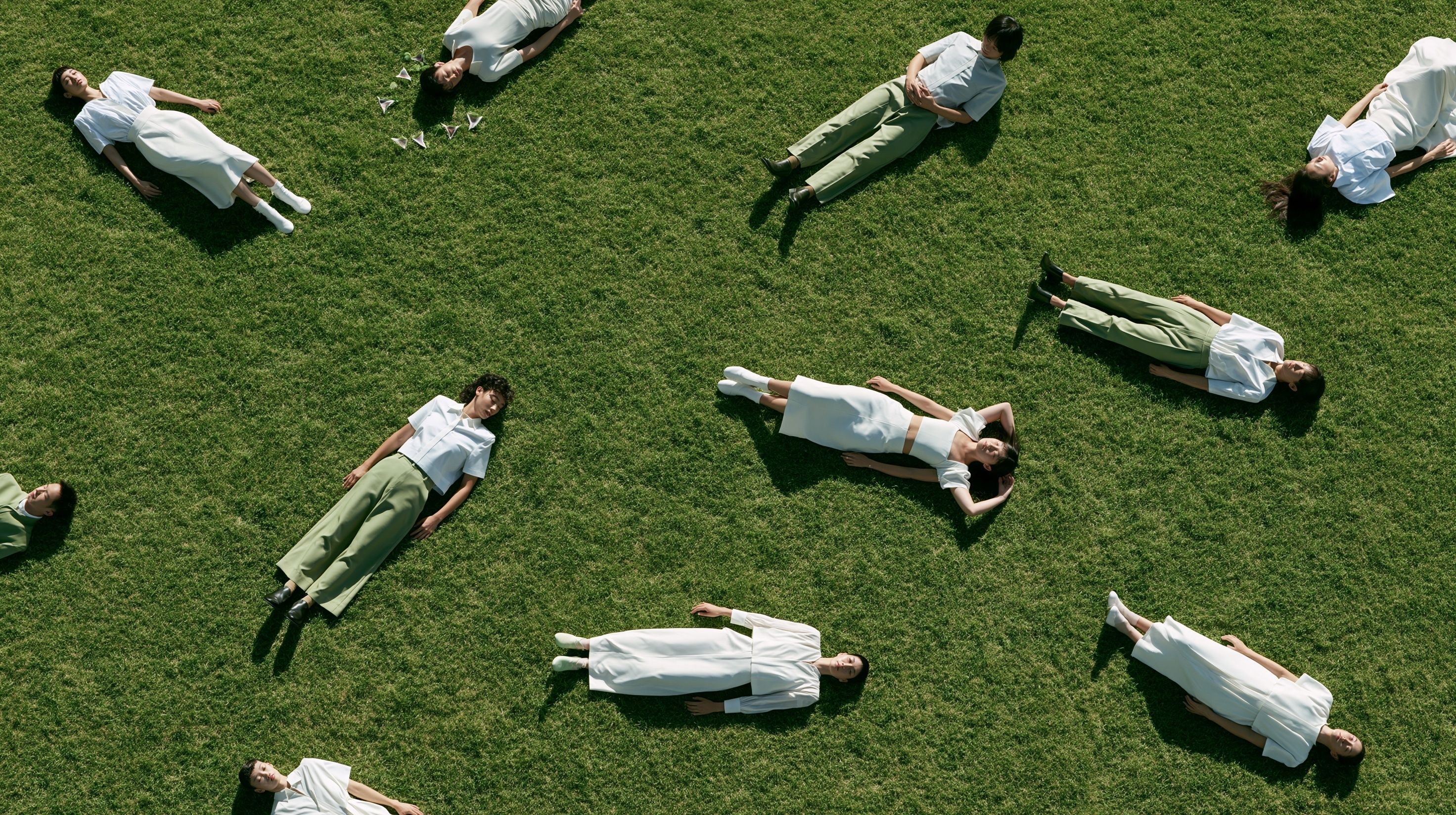 Humans in relaxed normcore fashion on bright green grass