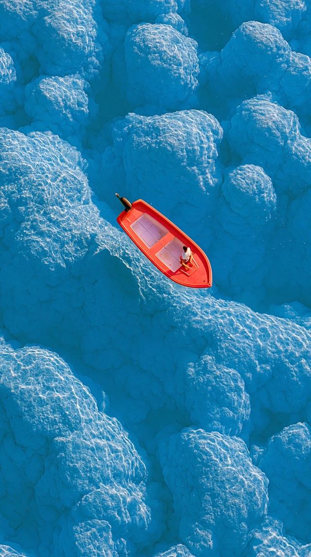 A stunning landscape features a beautiful water surface and a small red boat