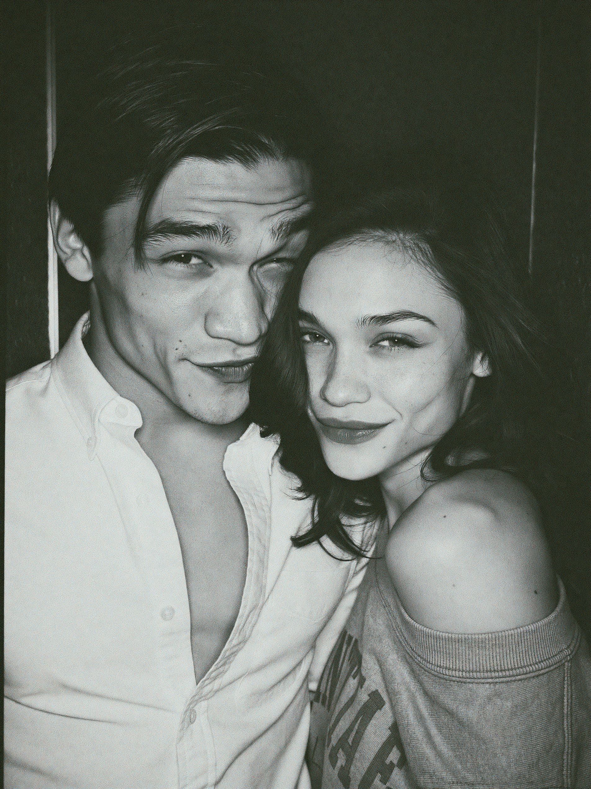 Una foto en blanco y negro realista de un guapo modelo masculino de moda euroasiático y una hermosa modelo femenina de moda blanca en un fotomatón.