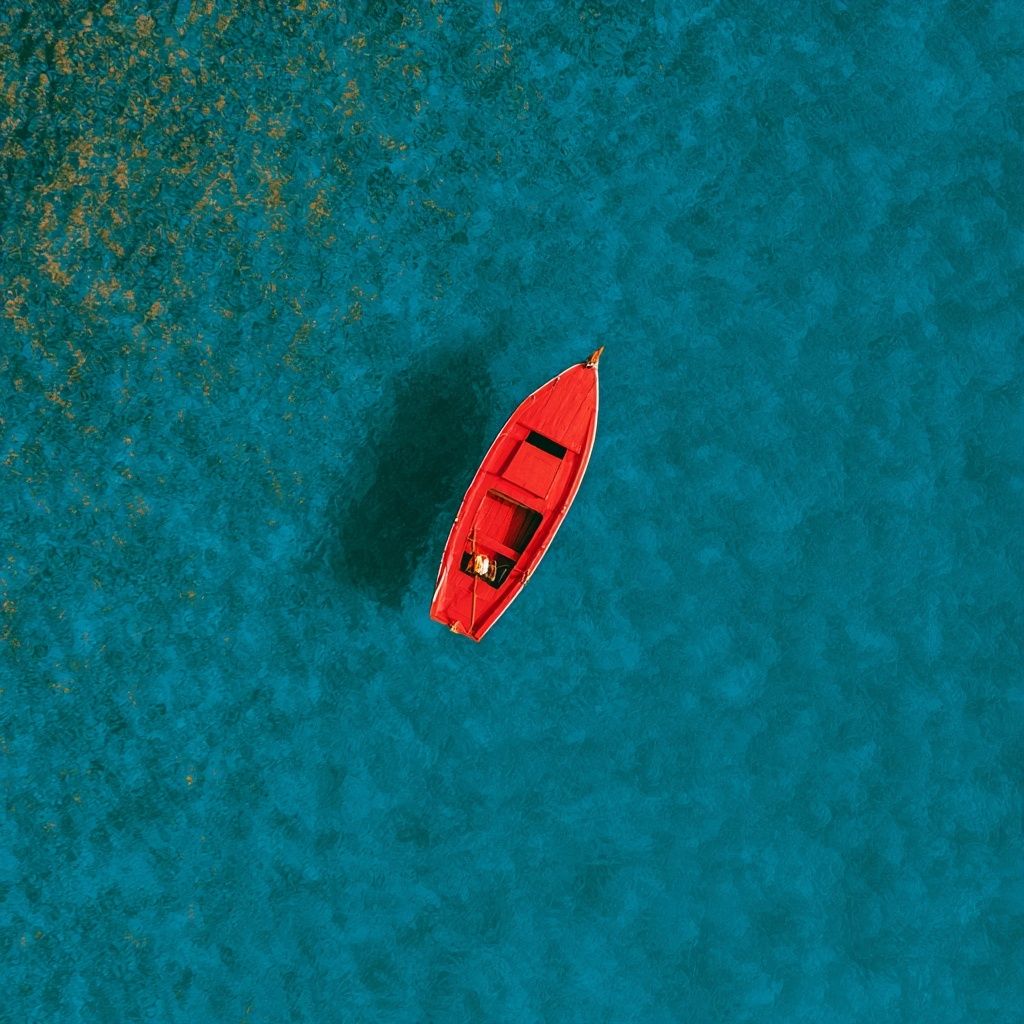 Paisaje sanador, impresionantemente hermoso. Superficie acuática azul vasta, composición minimalista y elegante con un barco rojo en una escena de paisaje diminuto.