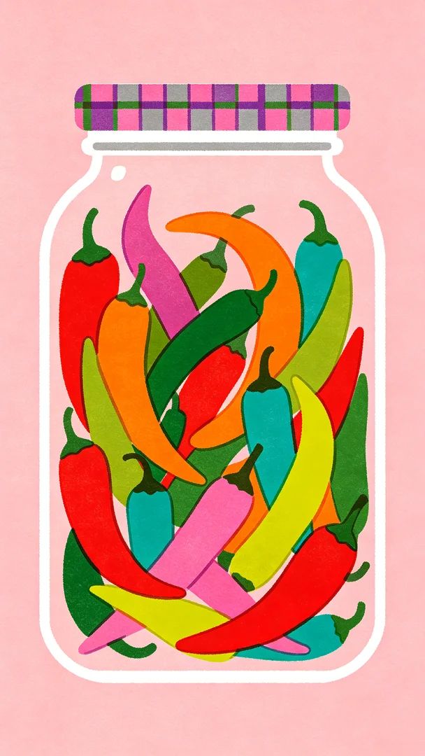 A vintage glass jar filled with various colors of long chili peppers